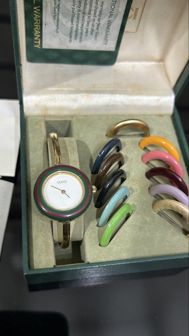 Vintage Gucci Change Bezel Bangle Watch Set (Category: Women's Watches) located in San Fernando. Submitted by TheBTBs (Listing ID 1465357965, Image 1). Description: - Authentic vintage Gucci watch set - Features a chic gold-tone bangle design - Includes multiple interchangeable colored bezels for versatile styling - Comes with original green presentation box - Includes international warranty card and paperwork booklets - Highly collectible and pe