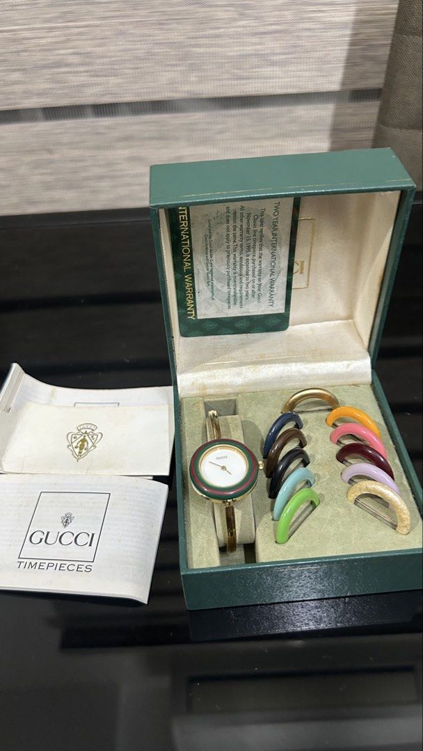 Vintage Gucci Change Bezel Bangle Watch Set (Category: Women's Watches) located in San Fernando. Submitted by TheBTBs (Listing ID 1465357965, Image 2). Description: - Authentic vintage Gucci watch set - Features a chic gold-tone bangle design - Includes multiple interchangeable colored bezels for versatile styling - Comes with original green presentation box - Includes international warranty card and paperwork booklets - Highly collectible and pe