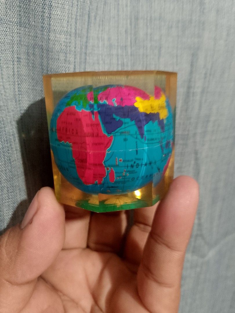 Vintage world globe map (Category: Stationery & School Supplies) located in Taguig. Submitted by generygwap31973 (Listing ID 1465376130, Image 1). Description: Mini globe encased in a transparent yellow resin block. Multi-colored continents printed on the inner sphere. Heavy enough to hold down papers on a desk. Compact hexagonal shape with flat sides. Fun accessory for a study table or office desk. Interesting conversation piece for map enthusia