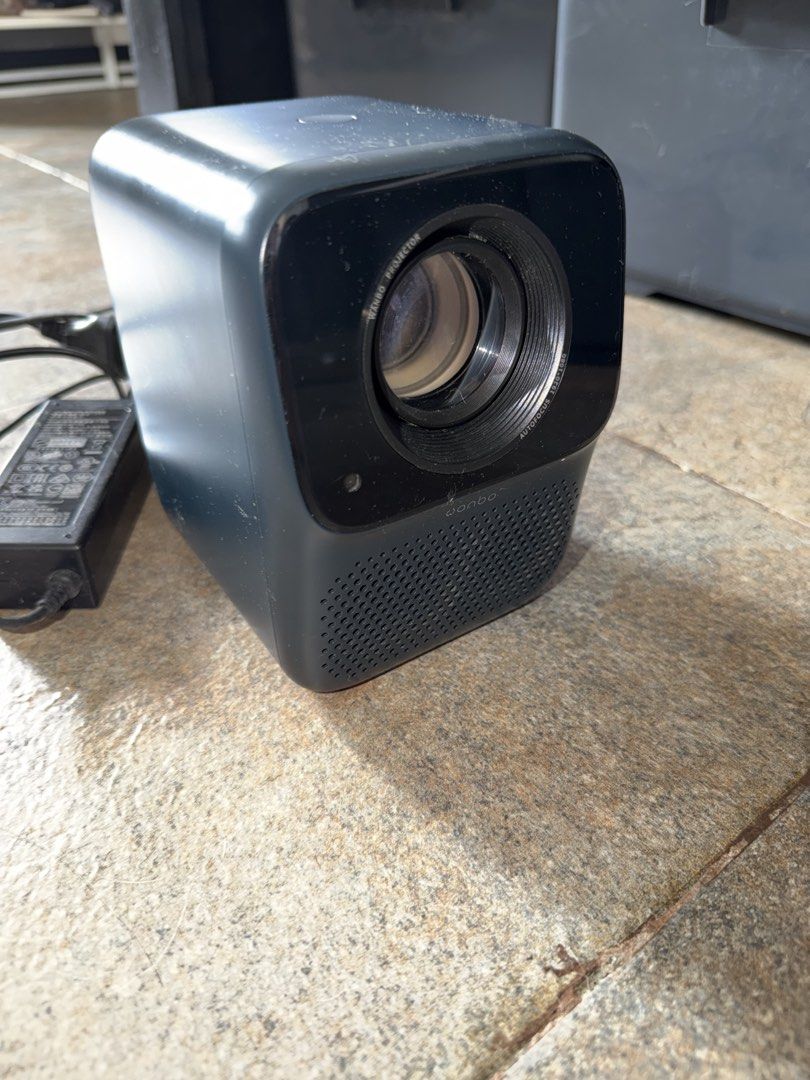 Wanbo Autofocus 1920x1080 Projector with Power Adapter (Category: Projectors) located in Manila. Submitted by malcolm_169 (Listing ID 1465194560, Image 1). Description: - Brand: Wanbo - Resolution: 1080p with autofocus - Color: Dark grey - Design: Compact cube with built-in speaker grille - Inclusions: Original power adapter plug - Condition: Powers on and ready to use, minor dust on casing from storage - Perfect for: Movie nights and presentatio