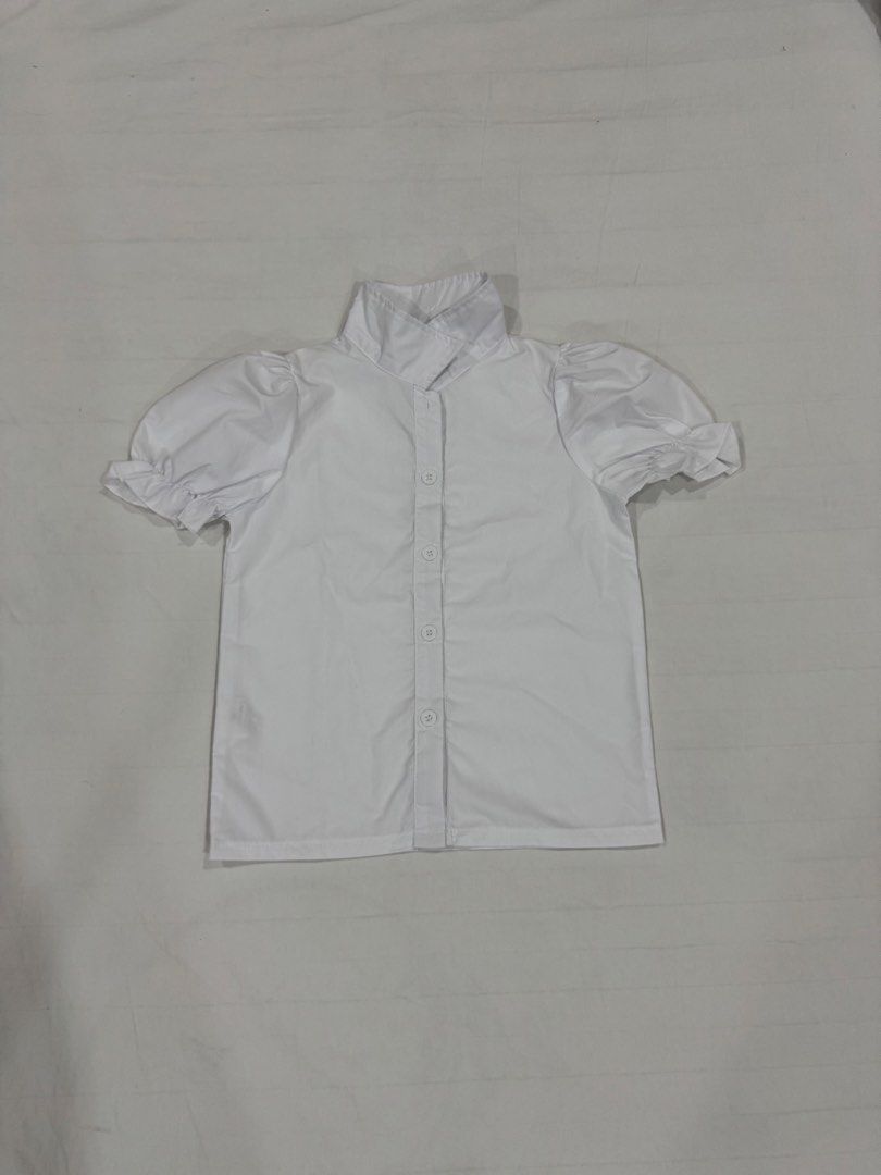 White Short Sleeve Puff Blouse with Collar (Category: Babies & Kids Fashion) located in Manila. Submitted by crazycat13 (Listing ID 1465171371, Image 1). Description: - Color: White - Style: Button-down blouse with short puff sleeves - Details: Structured high collar, clean front button closure, and charming ruffle cuffs - Fabric: Lightweight and comfortable - Versatility: Perfect for school, work, or casual chic outfits.