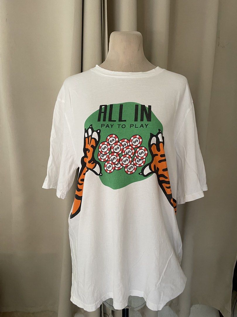 White Tiger All In cotton tee (Category: Shirts) located in Cainta. Submitted by zlove111 (Listing ID 1465193134, Image 1). Description: - Color: White - Fit: Relaxed fit with short sleeves - Design: Bold tiger and poker chips graphic with 'ALL IN PAY TO PLAY' text on the front - Back Details: '2022' text with a matching tiger tail graphic - Condition: Clean fabric with bright, high-quality screen-printed graphics - Style: Ideal streetwear piece 