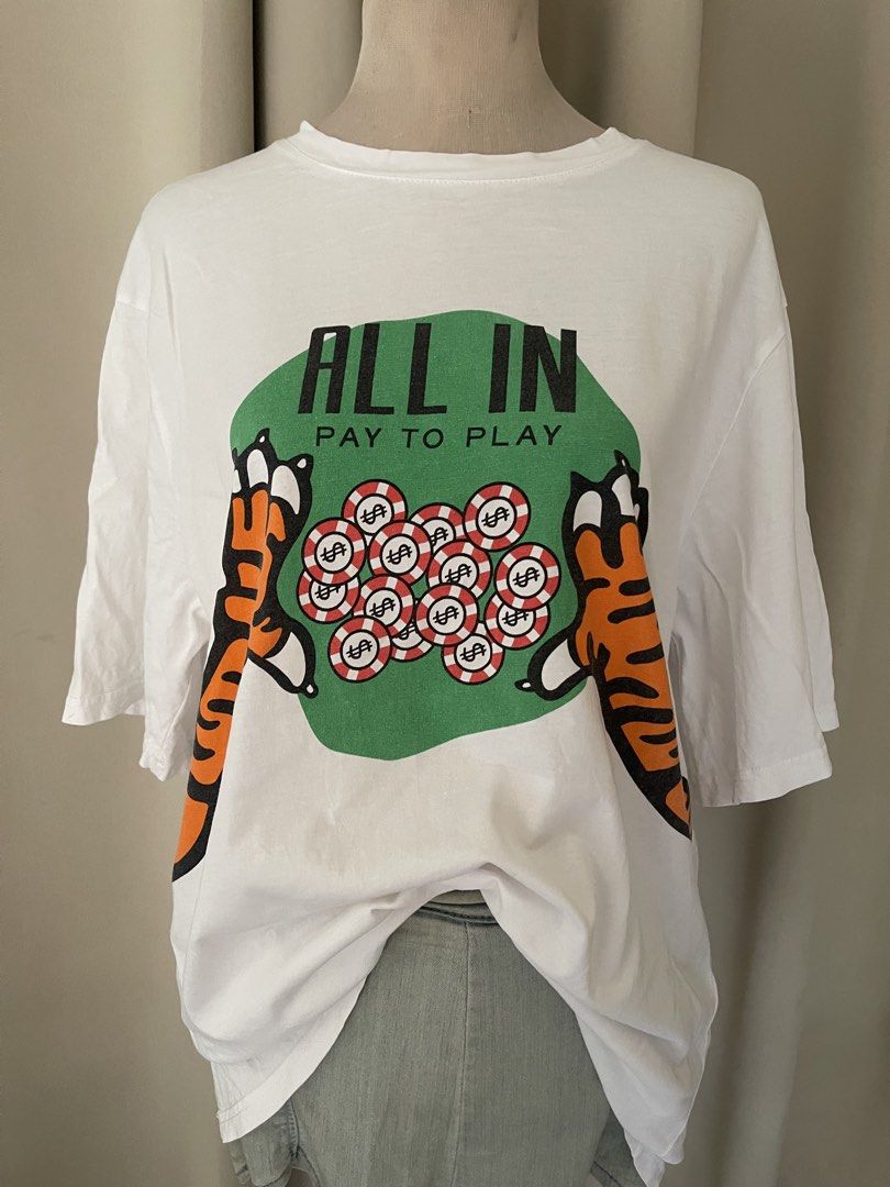 White Tiger All In cotton tee (Category: Shirts) located in Cainta. Submitted by zlove111 (Listing ID 1465193134, Image 2). Description: - Color: White - Fit: Relaxed fit with short sleeves - Design: Bold tiger and poker chips graphic with 'ALL IN PAY TO PLAY' text on the front - Back Details: '2022' text with a matching tiger tail graphic - Condition: Clean fabric with bright, high-quality screen-printed graphics - Style: Ideal streetwear piece 
