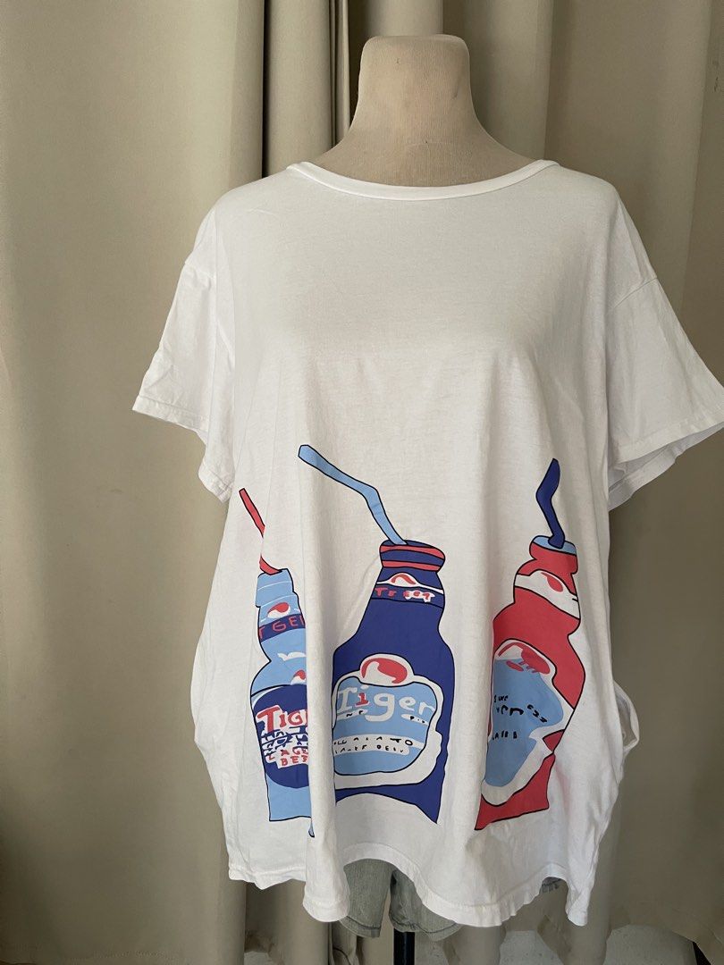 White Tiger Beer Graphic Tee (Category: Shirts) located in Cainta. Submitted by zlove111 (Listing ID 1465172288, Image 1). Description: - Color: White - Design: Large Tiger beer bottles & straws graphic - Fit: Relaxed, loose fit with short sleeves and crew neckline - Material: Lightweight, breathable cotton - Style: Fun casual streetwear, great for everyday wear.