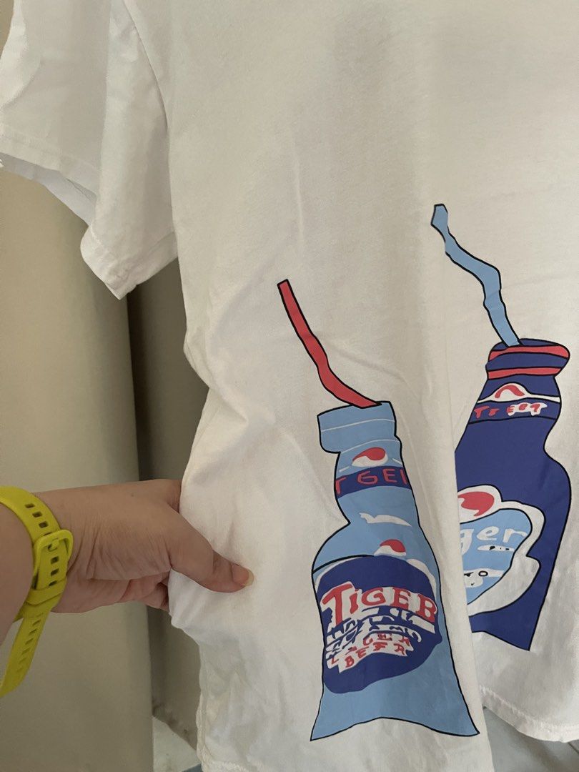 White Tiger Beer Graphic Tee (Category: Shirts) located in Cainta. Submitted by zlove111 (Listing ID 1465172288, Image 2). Description: - Color: White - Design: Large Tiger beer bottles & straws graphic - Fit: Relaxed, loose fit with short sleeves and crew neckline - Material: Lightweight, breathable cotton - Style: Fun casual streetwear, great for everyday wear.