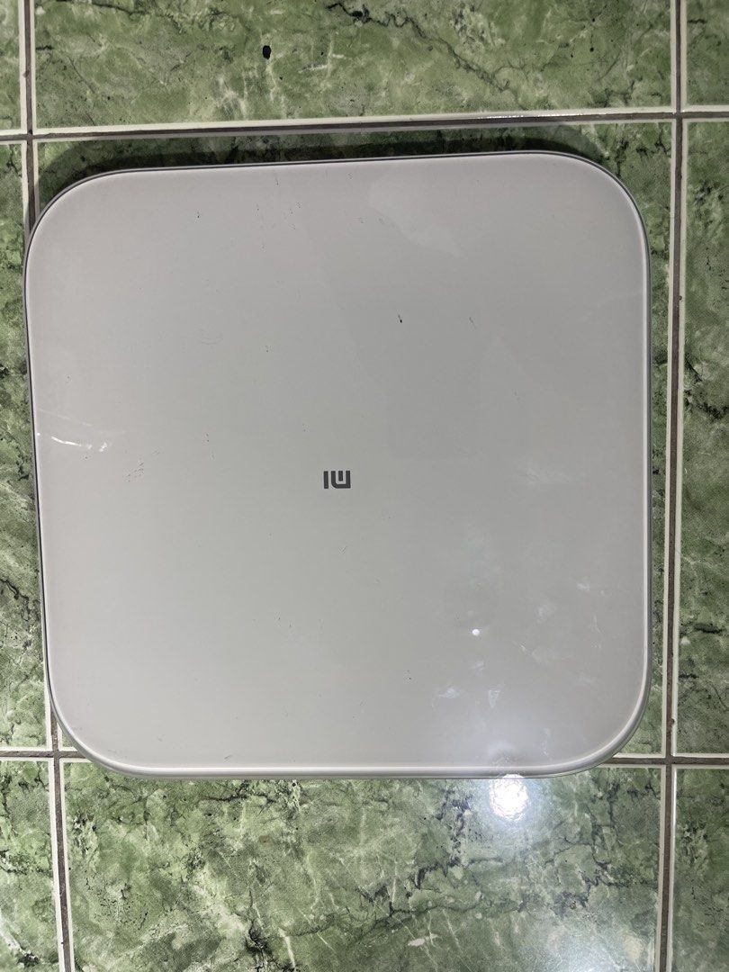 Xiaomi Mi Smart Scale 2 (Category: Health Monitors & Weighing Scales) located in Manila. Submitted by chesterson1979. (Listing ID 1465216124, Image 1). Description: Xiaomi smart scale model XMTZC04HM. White surface with gray Mi logo. Measures up to 150 kg. Requires 3 AAA batteries, currently takes standard Kingever batteries shown in slot. Bottom label lists manufacturing date May 2021. Dimensions measure roughly 28 by 28 centimeters square. Used