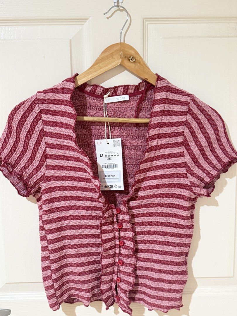 Zara Striped Ruffle Button-Front Top (Category: Blouses) located in Manila. Submitted by ktyyycloset (Listing ID 1465305764, Image 1). Description: - Brand: Zara - Condition: Brand new with tags (BNWT) - Size: Medium (true to size) - Color/Pattern: Red and pink stripes - Material: Textured knit fabric with great stretch - Details: Short sleeves, lettuce hem, plunging V-neckline, decorative front buttons - Original Retail Price: 1395 PHP - Style: 