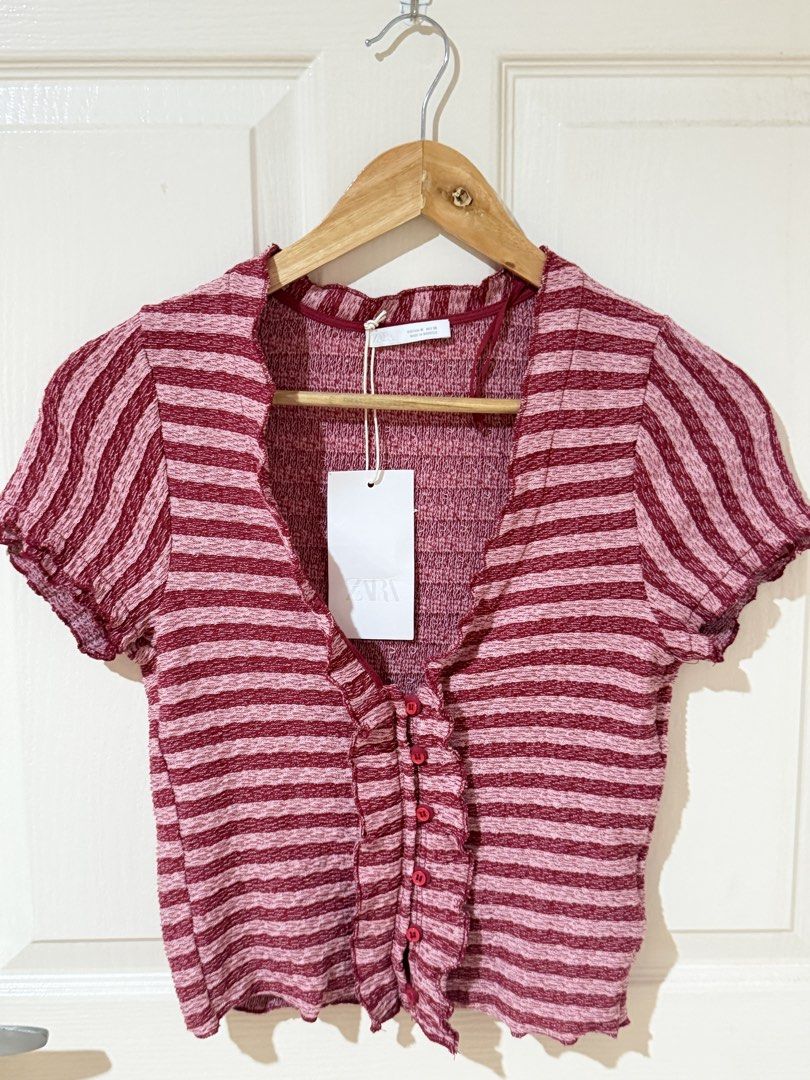 Zara Striped Ruffle Button-Front Top (Category: Blouses) located in Manila. Submitted by ktyyycloset (Listing ID 1465305764, Image 2). Description: - Brand: Zara - Condition: Brand new with tags (BNWT) - Size: Medium (true to size) - Color/Pattern: Red and pink stripes - Material: Textured knit fabric with great stretch - Details: Short sleeves, lettuce hem, plunging V-neckline, decorative front buttons - Original Retail Price: 1395 PHP - Style: 