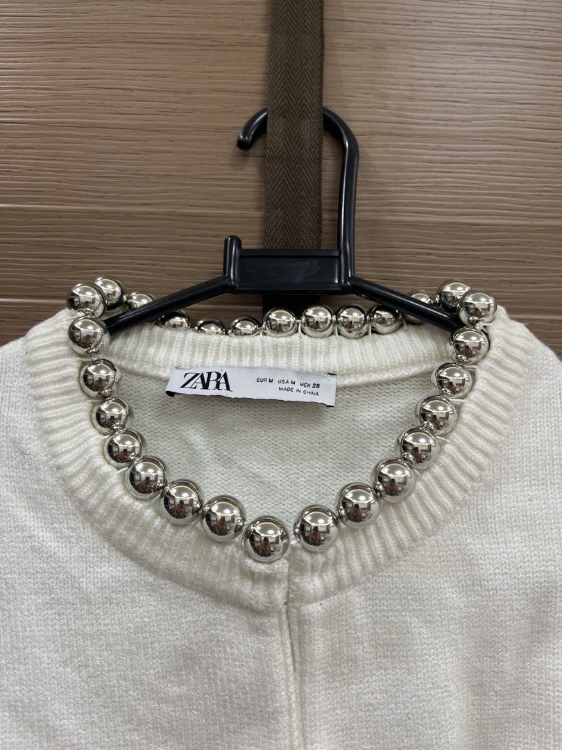 Zara White Cardigan With Silver Beads Size M (Category: Coats, Jackets and Outerwear) located in Mabalacat. Submitted by fashionclothesph (Listing ID 1465307398, Image 2). Description: - Brand: Zara - Size: M (tag attached) - Color: White - Style: Short-sleeve knit cardigan with silver metallic ball neckline embellishments - Details: Ribbed cuffs and hem - Material: 55% viscose, 25% polyester, 20% polyamide.