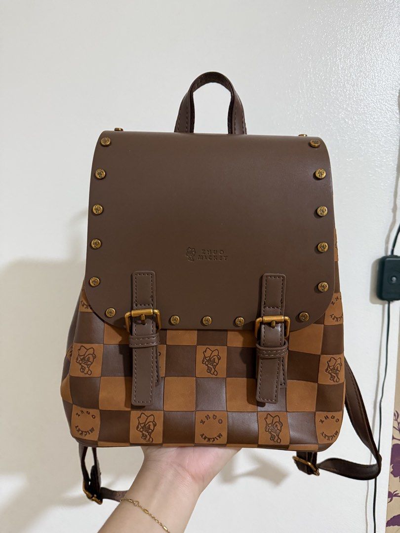 Zhuo Mickey brown checkered backpack (Category: Backpacks) located in Manila. Submitted by miksii_. (Listing ID 1465273349, Image 1). Description: - Brand: Zhuo Mickey - Color/Design: Brown checkered with brown leatherette flap - Details: Metal studs, buckle accents, engraved brand lettering on the base - Straps: Dual adjustable shoulder straps - Interior: Lined fabric with inner pockets (protective stuffing still inside) - Condition: Brand new, 