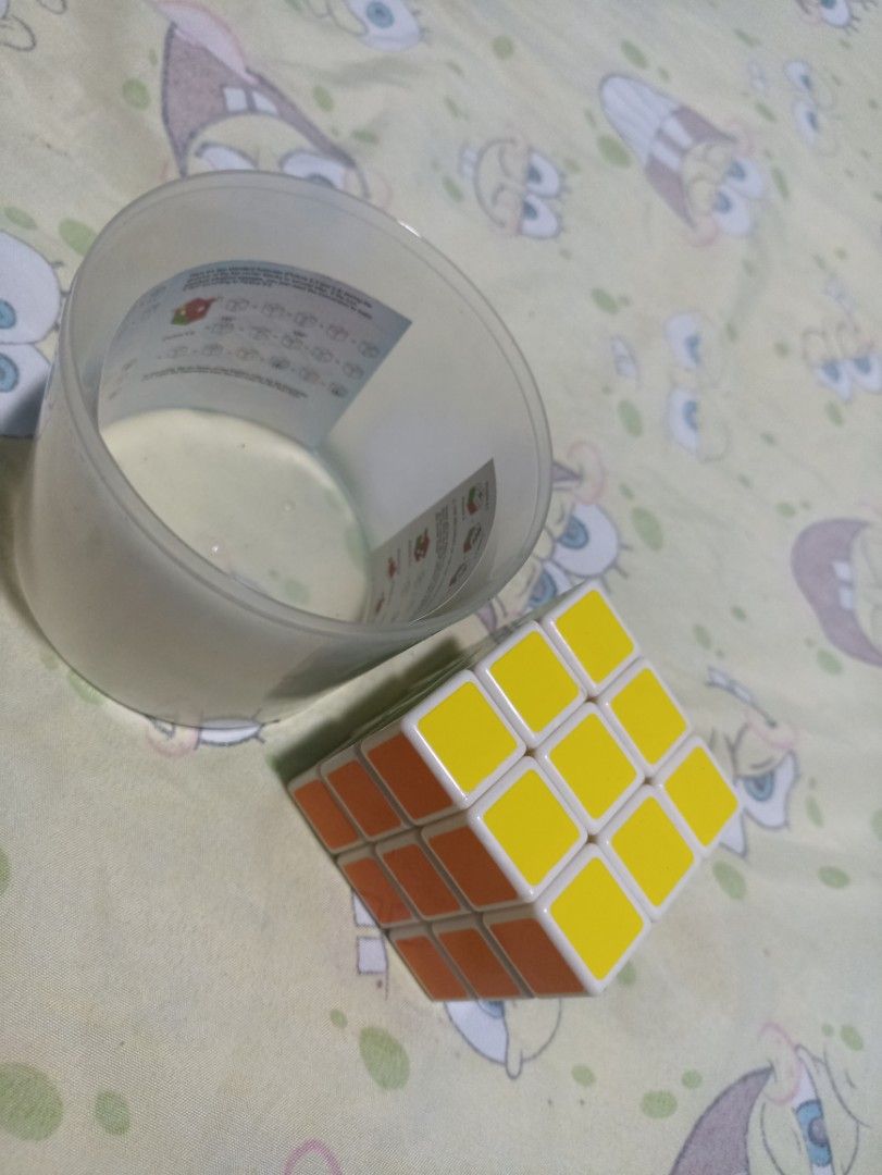 3x3 Rubik's cube with clear plastic container (Category: Board Games & Puzzles) located in Manila. Submitted by hobbymo_koleksyon.ph (Listing ID 1467088552, Image 1). Description: - Standard 3x3 puzzle toy - Smooth-turning tiles with a clean white plastic core - Includes a cylindrical clear plastic storage container - Comes with instruction diagrams printed on the label wrap - Perfect for beginners and speedcubers alike.
