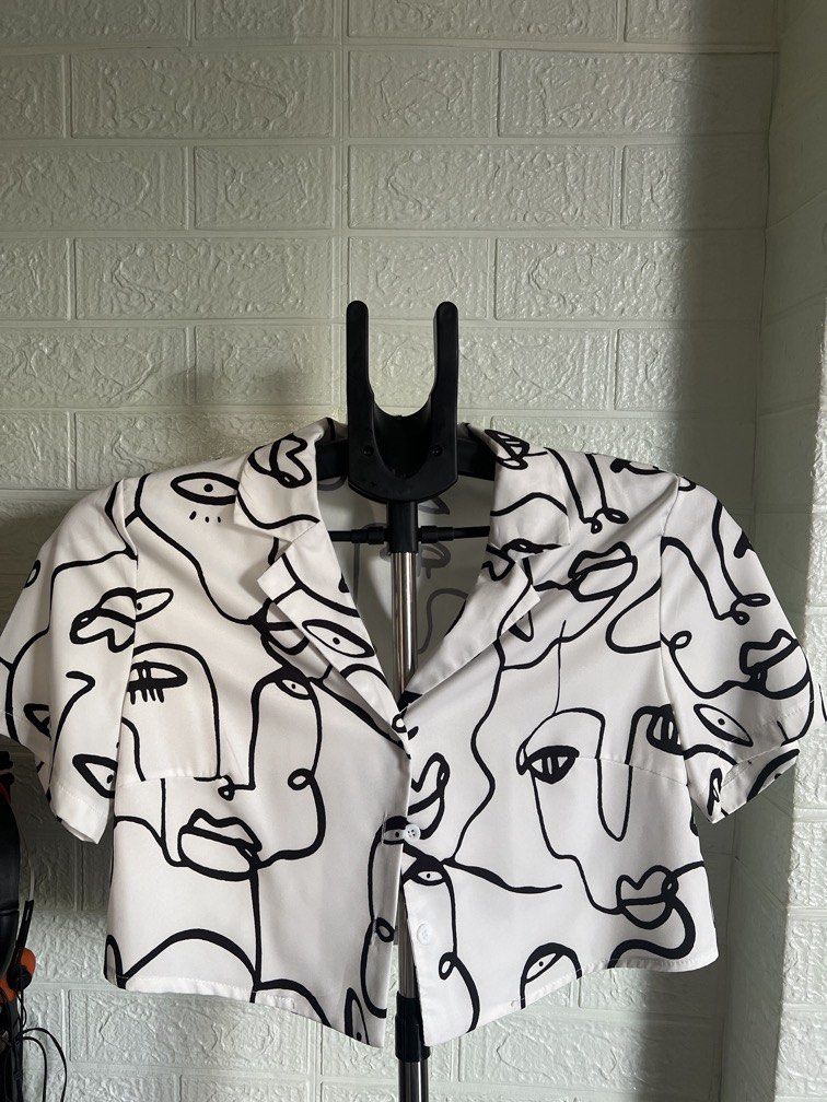 ABSTRACT FACE PRINT CROPPED BLOUSE (Category: Blouses) located in Dagupan City. Submitted by go.kluttery (Listing ID 1467042484, Image 1). Description: Color: White with black abstract face prints Style: Cropped button-up blouse Neckline: Collared Sleeves: Short sleeves Closure: Front buttons Design: Unique minimalist line-art print Fit: Relaxed, stylish silhouette Perfect for: Casual outings, cafe dates, travel, and OOTD looks.