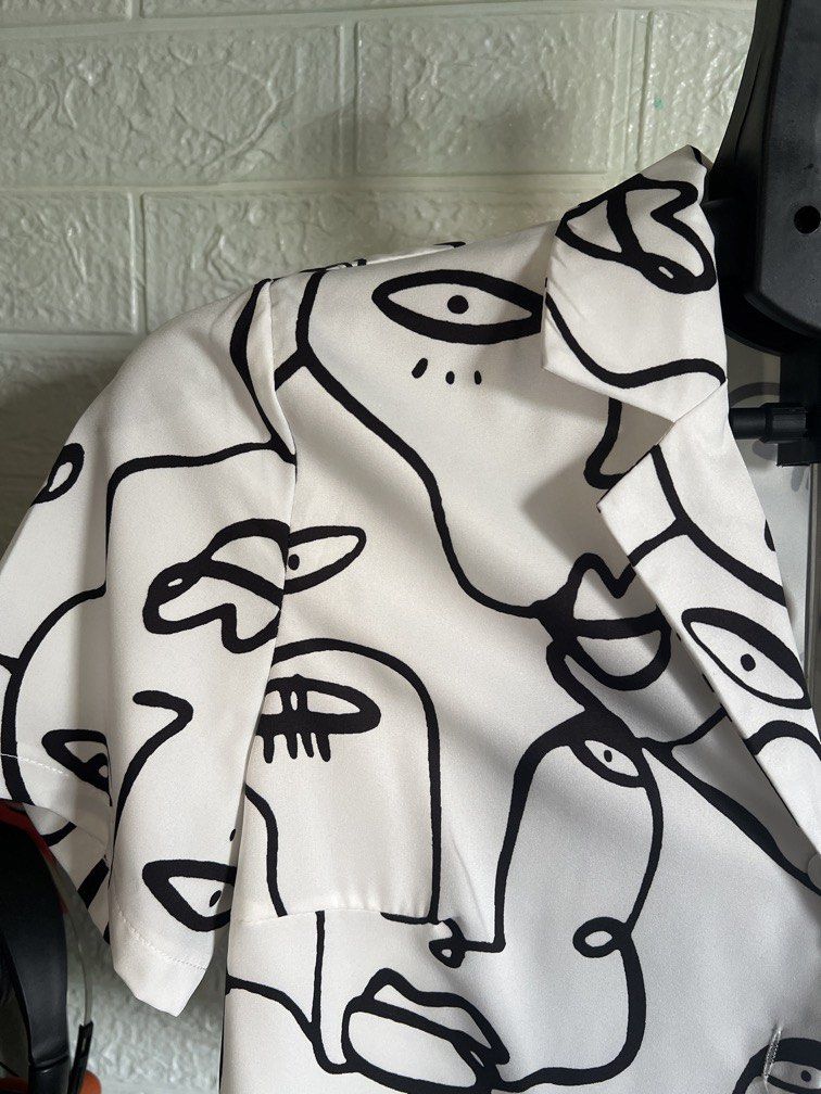 ABSTRACT FACE PRINT CROPPED BLOUSE (Category: Blouses) located in Dagupan City. Submitted by go.kluttery (Listing ID 1467042484, Image 3). Description: Color: White with black abstract face prints Style: Cropped button-up blouse Neckline: Collared Sleeves: Short sleeves Closure: Front buttons Design: Unique minimalist line-art print Fit: Relaxed, stylish silhouette Perfect for: Casual outings, cafe dates, travel, and OOTD looks.