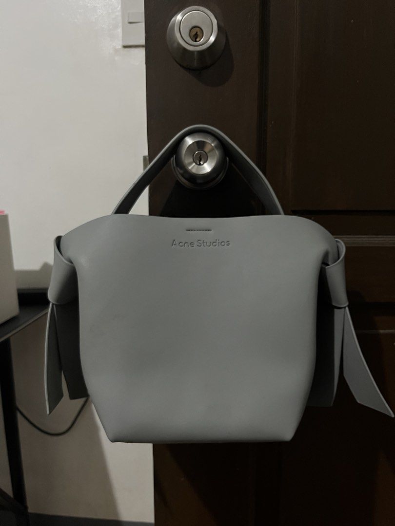 Acne Studios Grey Musubi Mini Bag (Category: Luxury Bags & Wallets) located in Mabalacat. Submitted by onlygrail.pamp (Listing ID 1467143030, Image 1). Description: - Brand: Acne Studios - Color: Grey - Material: Premium Leather - Condition: Barely any signs of wear (Pristine) - Hardware: Gold-tone with signature studs - Exterior: Clean front debossed logo lettering & signature knotted sides - Interior: Center zippered compartment divider and sna