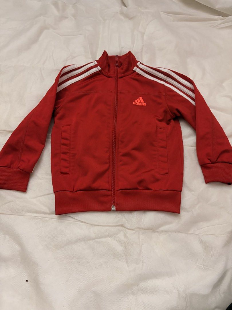 Adidas Red Track Jacket Kids (Category: Babies & Kids Fashion) located in Dasmarinas. Submitted by thriftcavite (Listing ID 1466987328, Image 1). Description: - Color: Vibrant red with classic white stripes - Design: Full zip front with ribbed collar, cuffs, and hem - Features: Two functional front pockets and Adidas chest logo - Condition: Excellent, with material and care tags still attached - Style: Versatile for workouts, streetwear, or casua