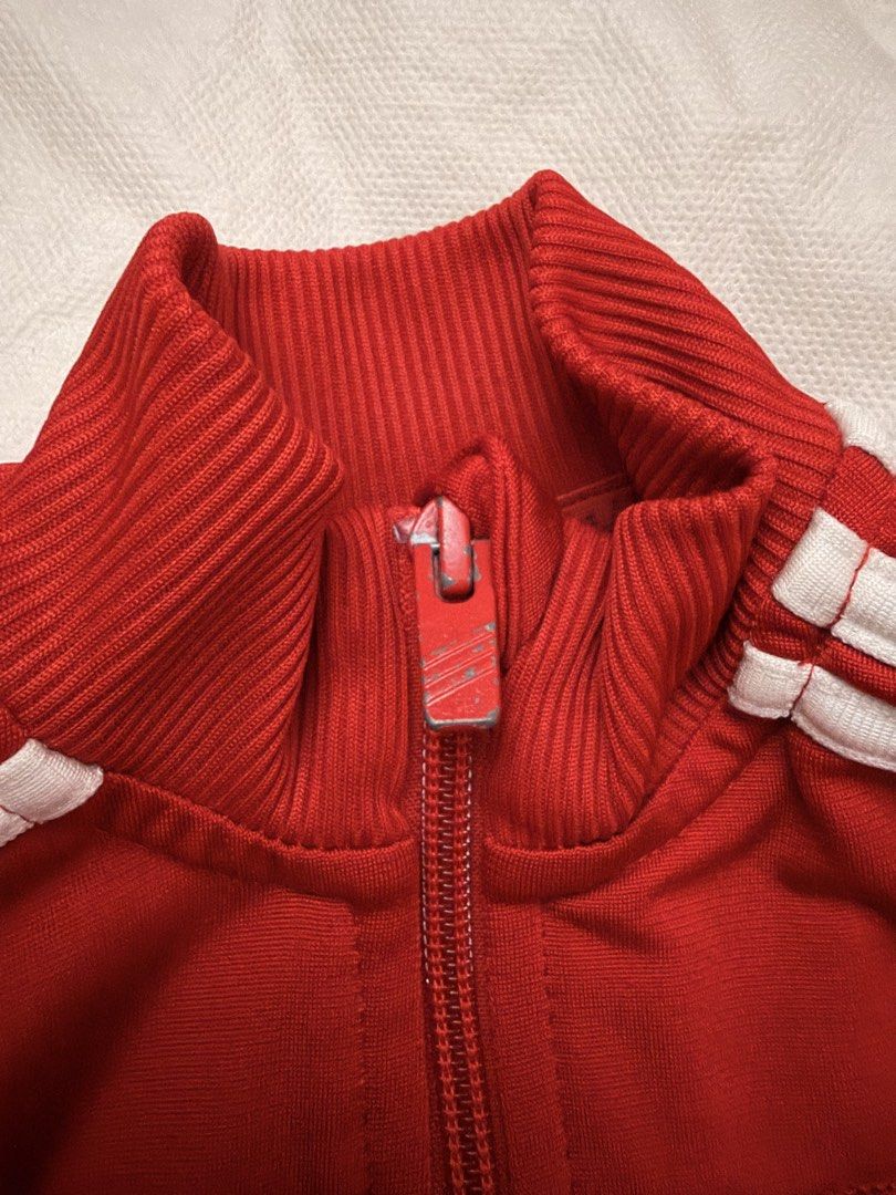 Adidas Red Track Jacket Kids (Category: Babies & Kids Fashion) located in Dasmarinas. Submitted by thriftcavite (Listing ID 1466987328, Image 2). Description: - Color: Vibrant red with classic white stripes - Design: Full zip front with ribbed collar, cuffs, and hem - Features: Two functional front pockets and Adidas chest logo - Condition: Excellent, with material and care tags still attached - Style: Versatile for workouts, streetwear, or casua