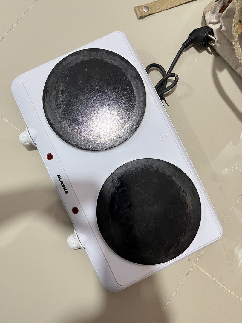 Alaska Double Hot Plate Electric Cooker (NEGO) (Category: Cookware & Accessories) located in Manila. Submitted by curated.clutter12 (Listing ID 1467006848, Image 1). Description: - Brand/Model: Alaska Double Hot Plate Cooker - Color: White - Design: Compact benchtop kitchen appliance with dual burners - Controls: Two side temperature control knobs with indicator lights - Power: Standard plug attached for easy setup - Condition: Shows typical surf