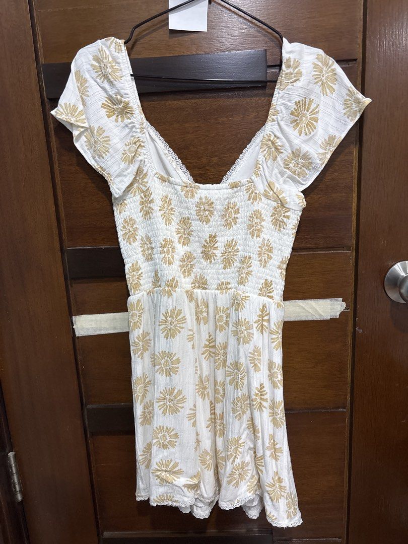 American Eagle White Floral Print Dress Medium (Category: Dresses) located in Mandaluyong City. Submitted by clothescarousel (Listing ID 1467122174, Image 3). Description: - Brand: American Eagle - Size: Medium - Color: White with gold-toned floral print - Design: Smocked bodice, sweetheart neckline, and short flutter sleeves - Details: Delicate lace trim along the collar edge - Fabric: Lightweight and breathable, ideal for warm weather or casual