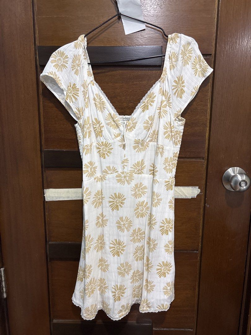 American Eagle White Floral Print Dress Medium (Category: Dresses) located in Mandaluyong City. Submitted by clothescarousel (Listing ID 1467122174, Image 1). Description: - Brand: American Eagle - Size: Medium - Color: White with gold-toned floral print - Design: Smocked bodice, sweetheart neckline, and short flutter sleeves - Details: Delicate lace trim along the collar edge - Fabric: Lightweight and breathable, ideal for warm weather or casual