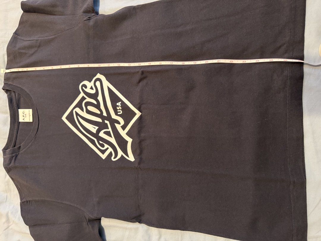 A.P.C. U.S. Logo Graphic Tee Black Medium (Category: Tshirts & Polo Shirts ) located in Quezon City. Submitted by pathdz (Listing ID 1467015672, Image 3). Description: - Brand: A.P.C. - Dimes: W19xL27 - Color: Black - Size: Medium (tag attached) - Design: White graphic print with diamond outline and bold script lettering on front - Origin: Made in California, USA - Condition: Clean fabric with minimal wear visible.