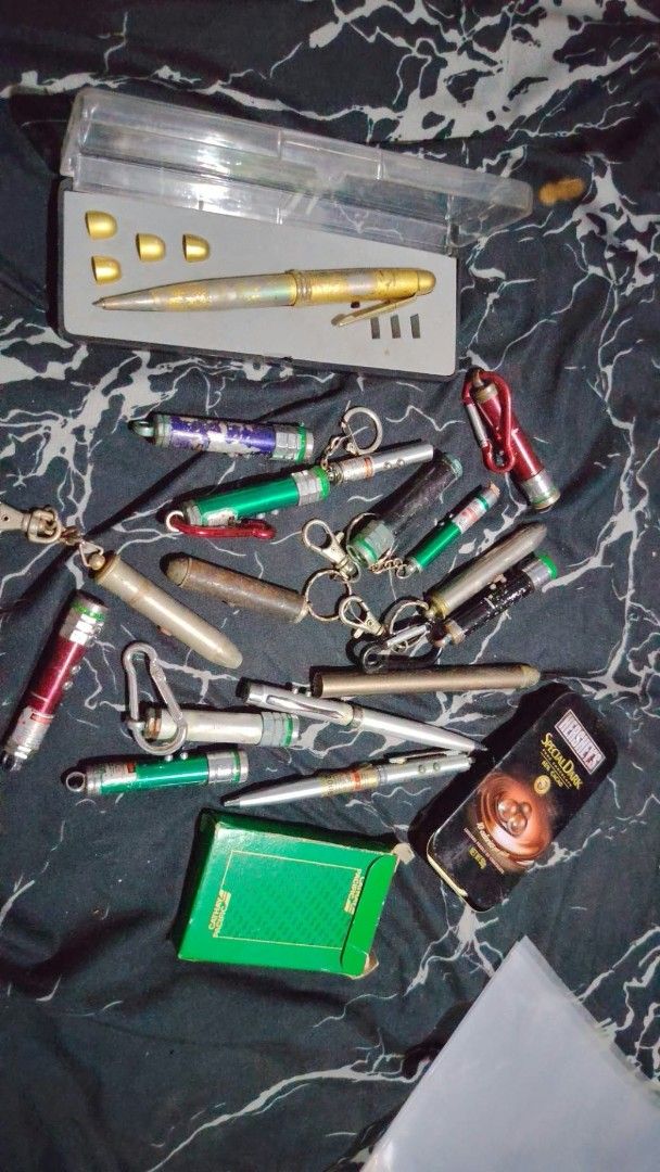 Assorted Laser Pointers Pens Keychains and Collectibles (Category: Stationery & School Supplies) located in Caloocan City. Submitted by chuaniki (Listing ID 1467154208, Image 1). Description: - Bulk lot of assorted items including laser pointers, metal pens, and keychains - Includes decorative boxes: Hershey's Special Dark tin and Cathay Pacific green box - Features a gold-toned pen in a transparent plastic case - Various designs and mixed condit
