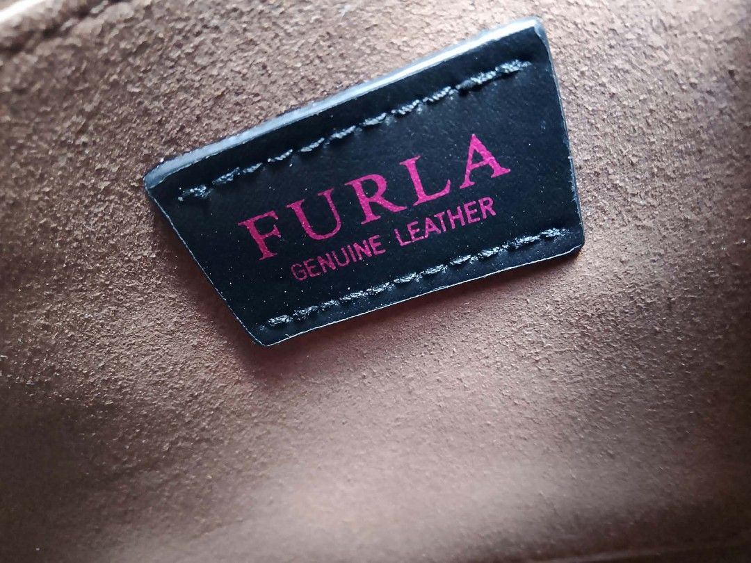 Authentic Furla 1927 Mini Top Handle with Myplay Charm™️ (Category: Luxury Bags & Wallets) located in Midsayap. Submitted by purse_gedo (Listing ID 1466997357, Image 3). Description: - Brand: Furla - Color: Navy blue leather with gold-tone hardware and red accents - Closure: Unique red rectangular clasp - Interior: Soft gray suede lining - Inclusions: Long adjustable shoulder strap and matching circular mirror charm - Condition: Clean overall, wi