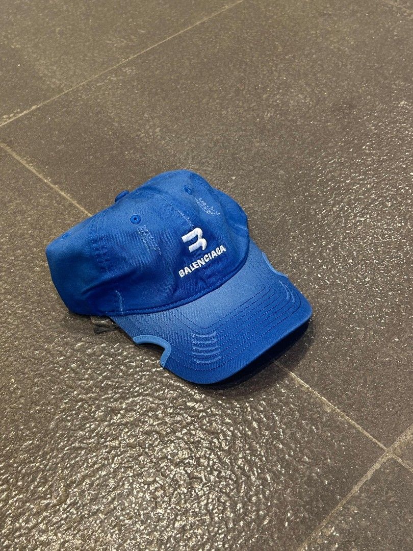 Balenciaga Blue Baseball Cap (Category: Caps & Hats) located in Pasig City. Submitted by paulclzdo (Listing ID 1467074457, Image 2). Description: - Brand: Balenciaga - Color: Bright blue with white embroidered logo - Condition: Excellent with inner tags intact - Details: Trendy distressed effects on brim and crown - Fit: Adjustable back strap with silver-tone metal buckle - Origin: Made in Italy - Perfect for daily streetwear and casual outfits.
