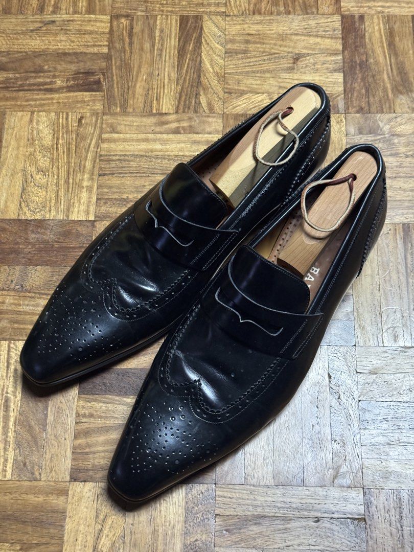 Bally Black Leather Wingtip Brogue Penny Loafers (Category: Dress Shoes) located in Manila. Submitted by seangoart (Listing ID 1467141575, Image 1). Description: - Brand: Bally - Style: Black leather penny loafers with wingtip brogue detailing and pointed toe - Design: Slip-on with saddle strap across the upper - Condition: Polished black finish with sturdy heels and minor creasing from normal wear - Bonus: Wooden shoe trees included to help keep