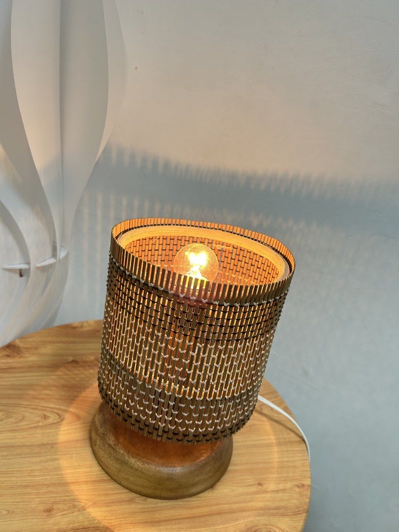 Bamboo wicker bedside table lamp with wooden base (Category: Lighting) located in Pateros City. Submitted by safewind_85fc6d (Listing ID 1467133751, Image 1). Description: - Cylindrical woven bamboo table lamp with solid round wooden base - Includes warm yellow bulb that creates cozy patterned shadows on walls - Cord with plug attached, ready to use - Ideal size for bedside tables, desks, or shelves - Perfect for adding a cozy, aesthetic vibe to 