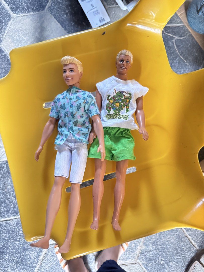 Barbie Ken Dolls with Outfits (Category: Kids Toys) located in Bulacan. Submitted by alshopie (Listing ID 1467140899, Image 1). Description: - Set of 2 male fashion dolls with blonde molded hair and standard poseable body joints - Doll 1 outfit: Blue patterned short-sleeve button-down shirt and white shorts - Doll 2 outfit: White Teenage Mutant Ninja Turtles (TMNT) graphic t-shirt and green shorts - Features painted facial features and barefoot d