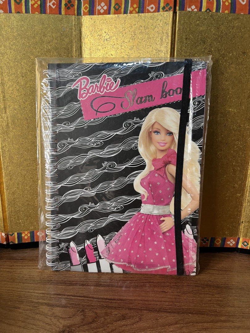Barbie Slam Book Spiral Notebook (Category: Stationery & School Supplies) located in Gapan. Submitted by lunashop14 (Listing ID 1467094928, Image 1). Description: - Official Mattel Licensed Product by Sterling Paper - Brand new and still sealed in plastic packaging - Features a chic black and white wave pattern cover with a pink elastic closure strap - Spiral binding for easy writing - Includes fun inside questionnaires like Pop Ups, Innermost, L