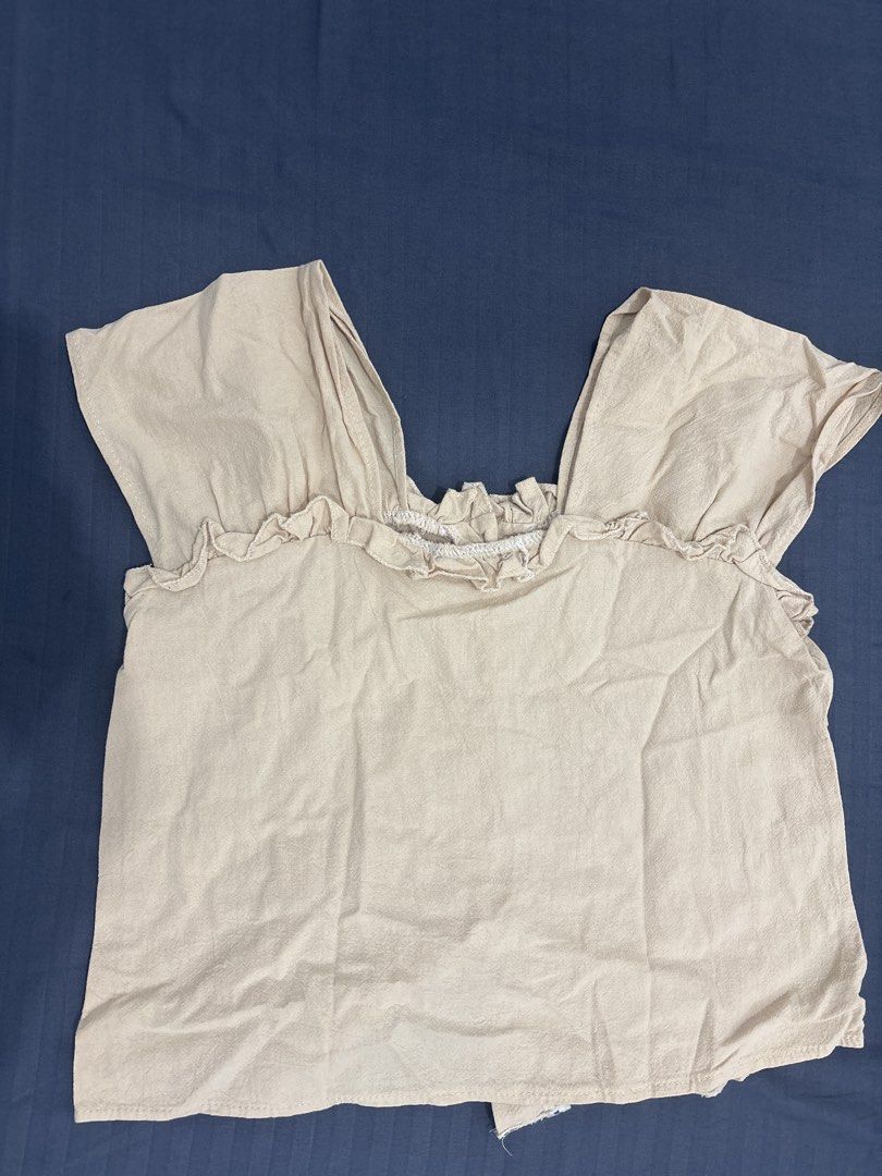 Beige Short Sleeve Ruffle Blouse with White Buttons (Category: Blouses) located in Makati City. Submitted by blueberrylime (Listing ID 1466974610, Image 3). Description: - Color: Versatile beige - Fit: Relaxed, free size - Material: Lightweight linen-like textured fabric - Design: Square neckline with cute ruffle trim on collar and shoulders - Closure: Front fastening with four round white buttons - Styling: Perfect to pair with skirts or high-wa