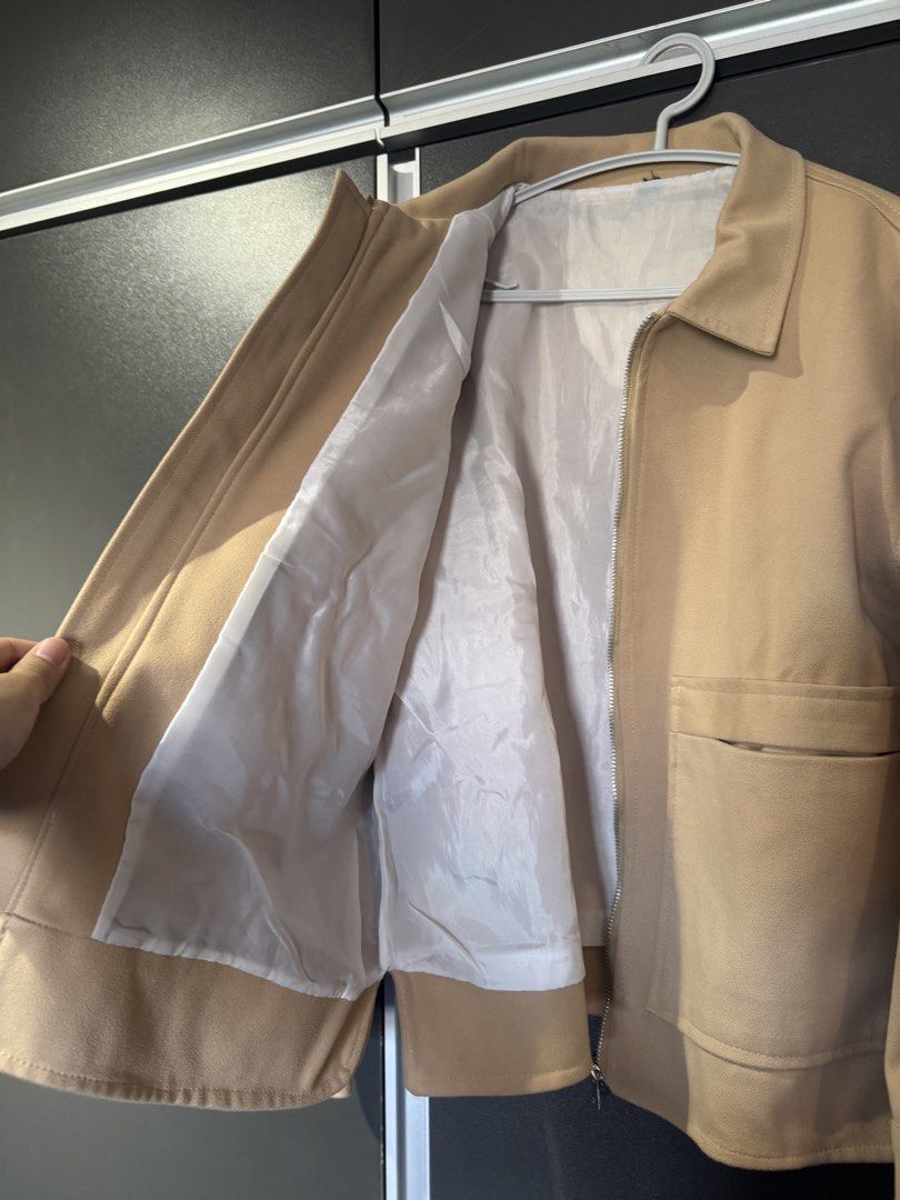 Beige Zip-Up Overshirt Jacket with Front Pockets (Category: Coats, Jackets and Outerwear) located in Dasmarinas. Submitted by akelvin23 (Listing ID 1467006572, Image 2). Description: - Color: Neutral beige - Design: Zip-up closure with classic collar - Pockets: Two large front patch pockets at the waist - Cuffs: Button cuffs with stylish tortoise-pattern buttons - Interior: Fully lined with smooth white fabric - Material: Heavy textured fabric ex