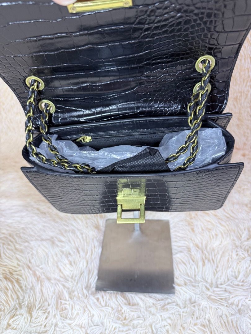 Black Crocodile Textured Shoulder Bag with Gold Hardware (Category: Shoulder Bags) located in Caloocan City. Submitted by hirahira.co (Listing ID 1467081344, Image 3). Description: - Elegant black shoulder bag with faux crocodile skin texture - Eye-catching gold-tone front clasp closure - Stylish woven black and gold chain strap - Clean interior featuring a convenient zipper pocket - Excellent, clean condition inside and out (comes packed with or