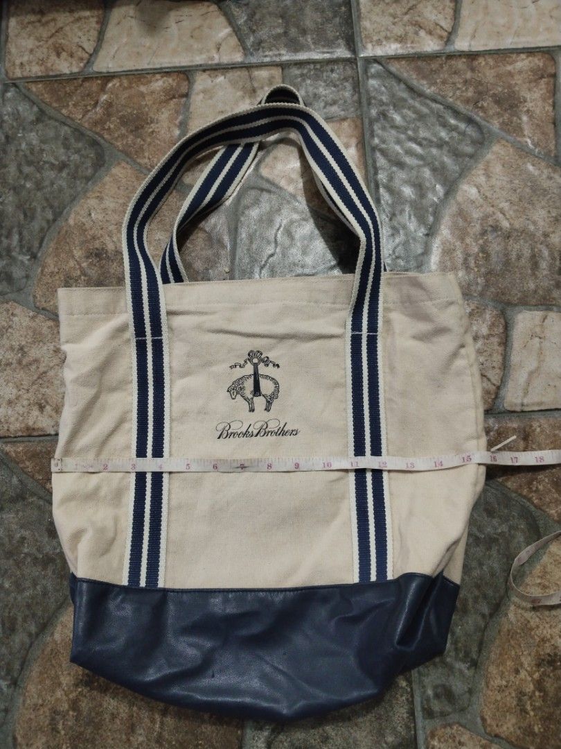 Brooks Brothers Tote Bag (Category: Tote Bags) located in Legazpi City. Submitted by genobecollectives (Listing ID 1467078372, Image 1). Description: Brooks Brothers tote bag 500 free ship - Color: Cream with dark blue accents and faux leather bottom - Design: Stylish blue and white striped shoulder straps - Interior: Spacious with matching striped lining - Size: Measures approximately 15 x 16 - Condition: Clean canvas body, light scratch sa iban