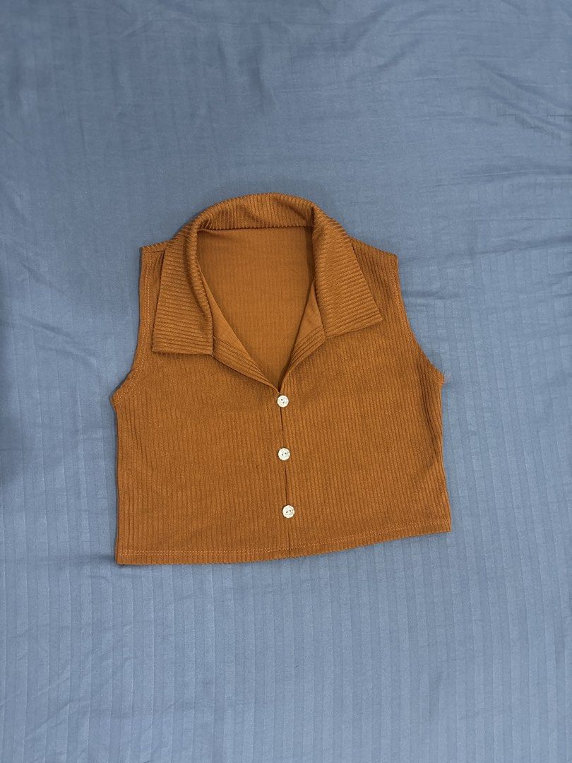 Brown Ribbed Collared Crop Top with Buttons (Category: Shirts) located in Makati City. Submitted by blueberrylime (Listing ID 1466973574, Image 1). Description: - Style: Sleeveless ribbed knit crop top - Color: Brown with three white front buttons - Design: Chic large fold-over collar - Fit: Stretchy, snug, hits around the waist - Versatility: Great for layering or wearing solo with high-waisted jeans.