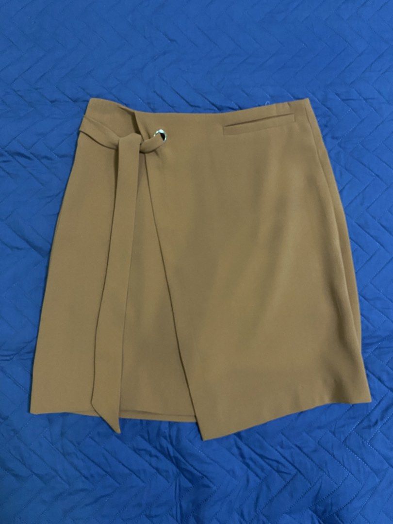 Brown Wrap Skirt Size S (Category: Skirts) located in Manila. Submitted by escherichiaa (Listing ID 1467139698, Image 1). Description: - Brand: Pantio - Size: Small - Color: Brown - Material: Textured twill weave - Features: Front flap overlay with built-in belt loop and strap accent, side zipper closure - Style: Great for work or casual outings - Condition: Excellent.