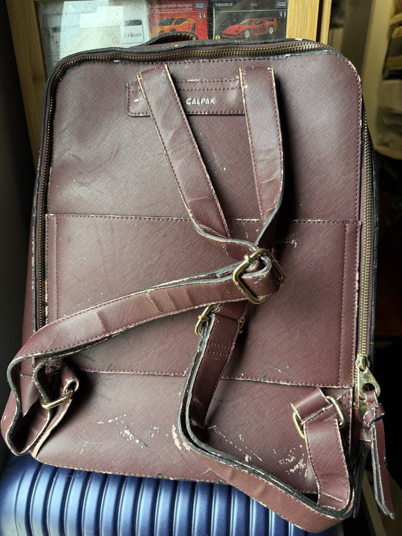 Calpak Red Wine Faux Leather Backpack (Category: Backpacks) located in Dasmarinas. Submitted by mspigrabbit (Listing ID 1467036111, Image 2). Description: - Brand: Calpak - Color: Red Wine/Maroon - Design: Structured shape with zip-around closure, front zippered pocket, and woven stitch detailing - Hardware: Smooth-working metal zippers and adjustable shoulder straps - Condition: Heavy exterior scuffing and faux leather peeling along the edges, s