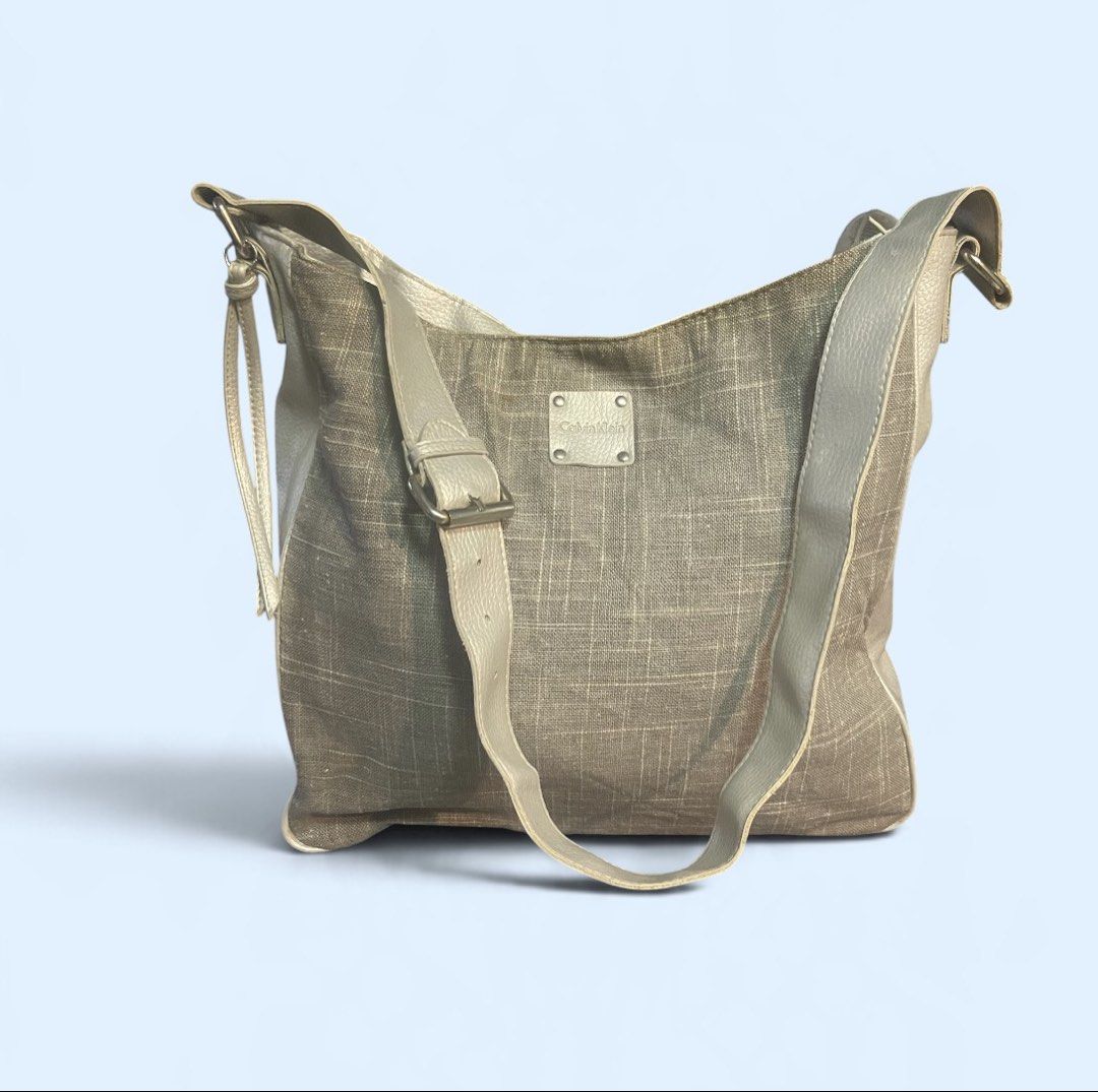 Calvin Klein Grey Crossbody Shoulder Bag - Authentic (Category: Cross-body Bags) located in San Pedro. Submitted by lifebeginsaftercoff33 (Listing ID 1467072243, Image 2). Description: - Authentic Calvin Klein crossbody shoulder bag - Chic grey woven texture canvas fabric with solid grey faux leather trim - Adjustable strap with buckle and sleek branded front metal plaque - Secure magnetic snap top closure - Roomy slouchy interior lined with CK l