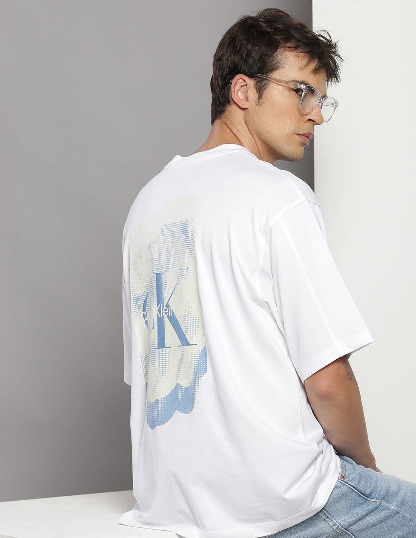 Calvin Klein Jeans Embroidered Monogram Graphic Tee (Category: Tshirts & Polo Shirts ) located in Baliuag. Submitted by retrovault83 (Listing ID 1467132047, Image 1). Description: ✨ Condition: 9/10 – Excellent Preloved Condition 📏 Measurements (Flat Lay, Tagged Size S - Relaxed Fit): • Pit to Pit: 23 • Length: 27.5 ✅ Details: • Clean white body featuring a minimal embroidered tonal "cK" logo on the left chest • Eye-catching abstract back graphic