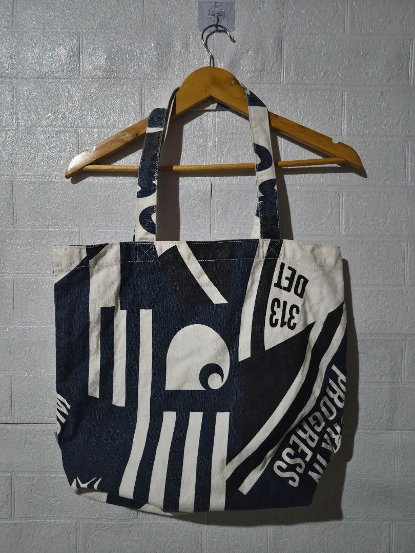 Carhartt Work In Progress Printed Canvas Tote Bag (Category: Tote Bags) located in Ilagan. Submitted by culalabejen05 (Listing ID 1466977894, Image 1). Description: - Brand: Carhartt Work In Progress (WIP) - Color: Navy blue and white with exterior graphic print - Material: Sturdy, durable canvas fabric - Design: Open top with dual shoulder straps - Interior: Includes a slip pocket with number graphics and official brand tag - Usage: Spacious eve