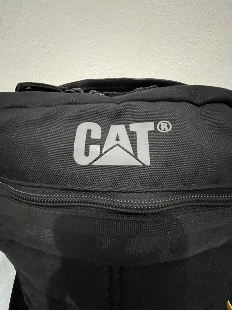 Caterpillar CAT Black Messenger Crossbody Bag (Category: Sling Bags) located in Talisay. Submitted by cherylu (Listing ID 1466975549, Image 2). Description: Black CAT crossbody bag made from sturdy canvas material. Features a large front zipped compartment and adjustable shoulder strap. Interior lined with black fabric and branded Caterpillar logo patch inside and outside. Yellow CATERPILLAR tag attached on the side. Great everyday bag for carryi
