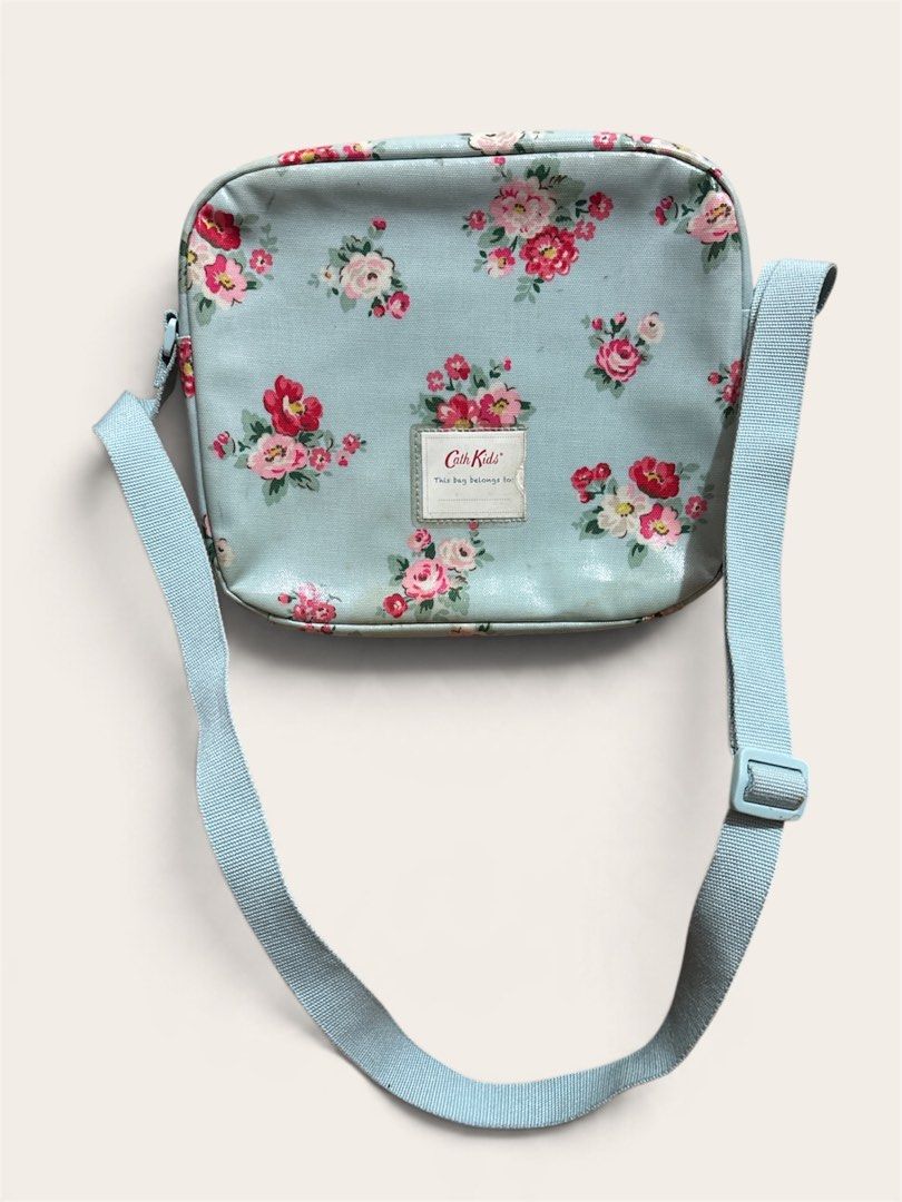 Cath Kids London Insulated Lunch bag (Category: Travel Essentials & Accessories) located in Pasig City. Submitted by burtonxxx (Listing ID 1467074708, Image 2). Description: - Brand: Cath Kidston Kids Collection - Design: Light blue background with charming pink rose floral print - Interior: Insulated foil lining to keep food and snacks fresh - Features: Adjustable crossbody strap and front name tag slot ("This bag belongs to") - Closure: Secure 