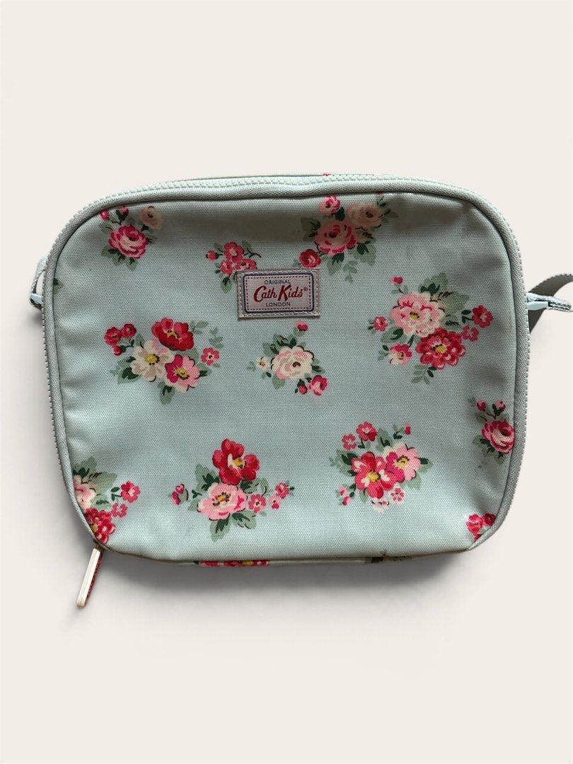 Cath Kids London Insulated Lunch bag (Category: Travel Essentials & Accessories) located in Pasig City. Submitted by burtonxxx (Listing ID 1467074708, Image 1). Description: - Brand: Cath Kidston Kids Collection - Design: Light blue background with charming pink rose floral print - Interior: Insulated foil lining to keep food and snacks fresh - Features: Adjustable crossbody strap and front name tag slot ("This bag belongs to") - Closure: Secure 
