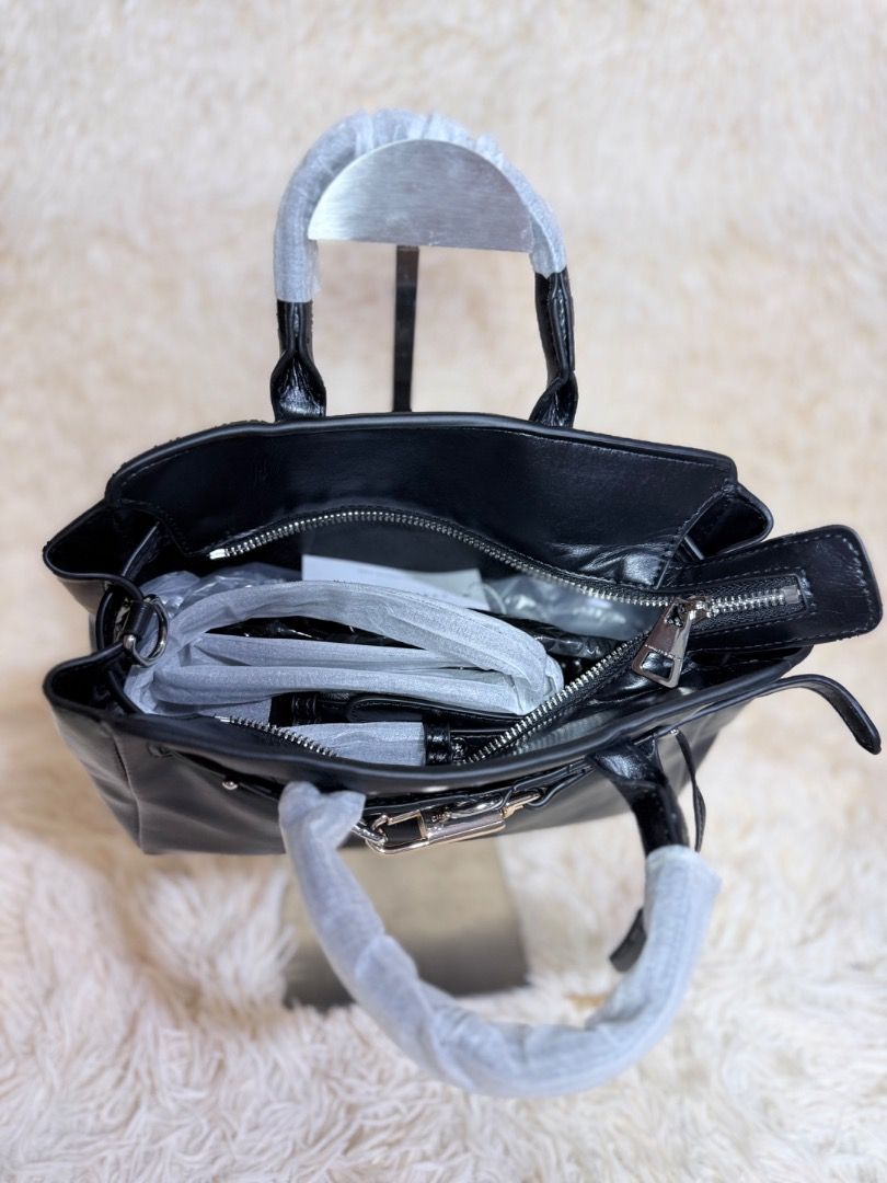 Charles & Keith Black Handbag (Category: Luxury Bags & Wallets) located in Caloocan City. Submitted by hirahira.co (Listing ID 1467082592, Image 3). Description: - Brand: Charles & Keith - Color & Finish: Black with a smooth, glossy finish - Hardware: Silver-tone hardware - Handles: Dual top handles (still wrapped in protective foam) - Details: Decorative front belt detail and attached padlock charm with keys - Compartment: Secure zippered main c