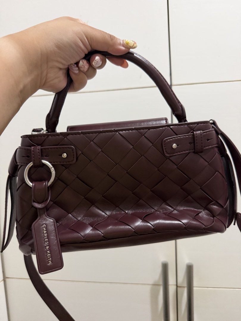 Charles & Keith Interwoven Burgundy Handbag (Category: Luxury Bags & Wallets) located in Davao. Submitted by pamdyclutters (Listing ID 1467140927, Image 2). Description: - Brand: Charles & Keith - Color: Rich Burgundy with silver-toned hardware and studs - Design: Stylish woven pattern across the body - Versatility: Includes a sturdy top handle and a removable shoulder strap - Extras: Features a chic branded luggage tag on the side ring - Interio