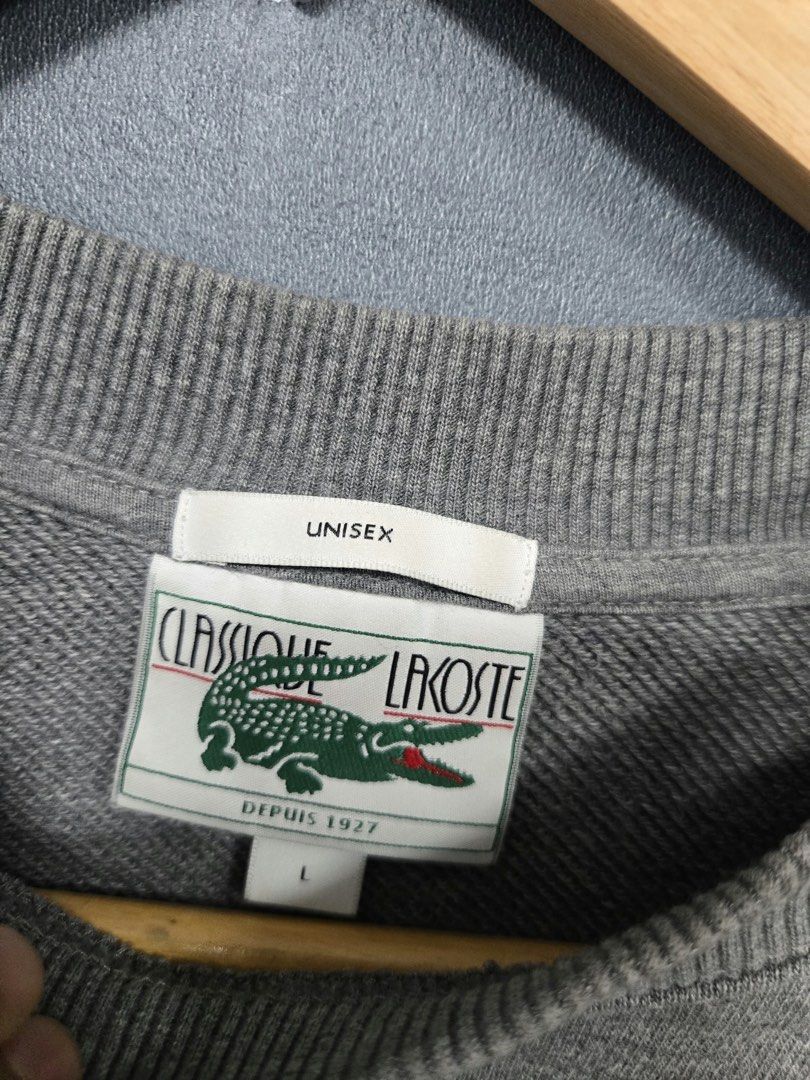 Classique Lacoste Unisex Grey Sweatshirt (Category: Coats, Jackets and Outerwear) located in Tarlac. Submitted by adivans (Listing ID 1466973016, Image 2). Description: - Brand: Lacoste - Style: Classic crewneck sweatshirt - Color: Grey - Size: Large (Unisex fit) - Material: Heavy cotton fleece - Details: Large circular crocodile chest graphic, ribbed cuffs, collar, and hem - Condition: Great for casual layering.