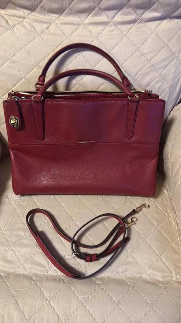 Coach Red Leather Shoulder Bag with Strap (Category: Luxury Bags & Wallets) located in Pasay City. Submitted by ccpetitte (Listing ID 1466971380, Image 1). Description: - Brand: Coach - Color: Rich Red - Material: Premium pebbled leather with gold-tone hardware - Compartments: Double zip top compartments with a clean interior structure and structured base - Handles/Strap: Sturdy grab handles plus an adjustable and detachable shoulder strap - Bran