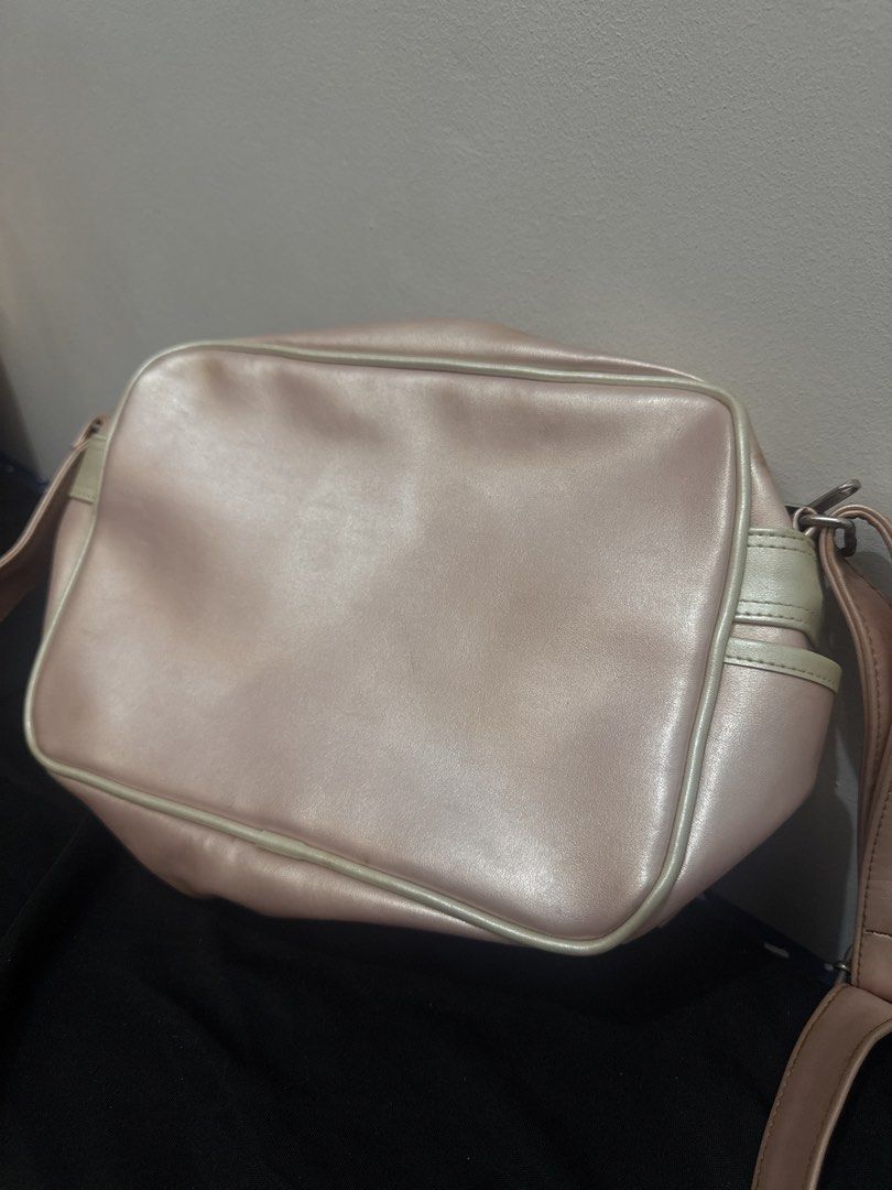Converse Pink Shoulder Bag (Category: Shoulder Bags) located in Manila. Submitted by sstash444 (Listing ID 1467118242, Image 3). Description: - Brand: Converse - Style: Messenger bag - Color: Pink with red logo lettering - Features: Perforated front panel, zip top opening, and adjustable shoulder strap - Condition: Clean overall shape with minor surface staining near the top trim and front lettering.