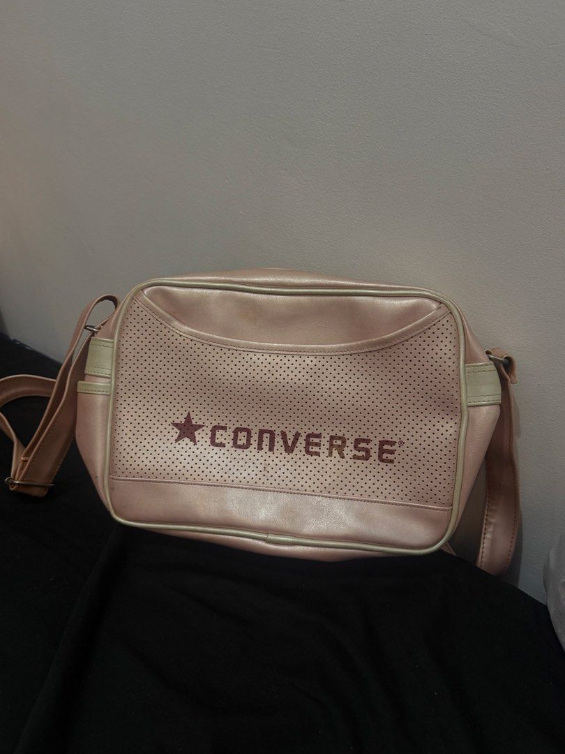 Converse Pink Shoulder Bag (Category: Shoulder Bags) located in Manila. Submitted by sstash444 (Listing ID 1467118242, Image 2). Description: - Brand: Converse - Style: Messenger bag - Color: Pink with red logo lettering - Features: Perforated front panel, zip top opening, and adjustable shoulder strap - Condition: Clean overall shape with minor surface staining near the top trim and front lettering.